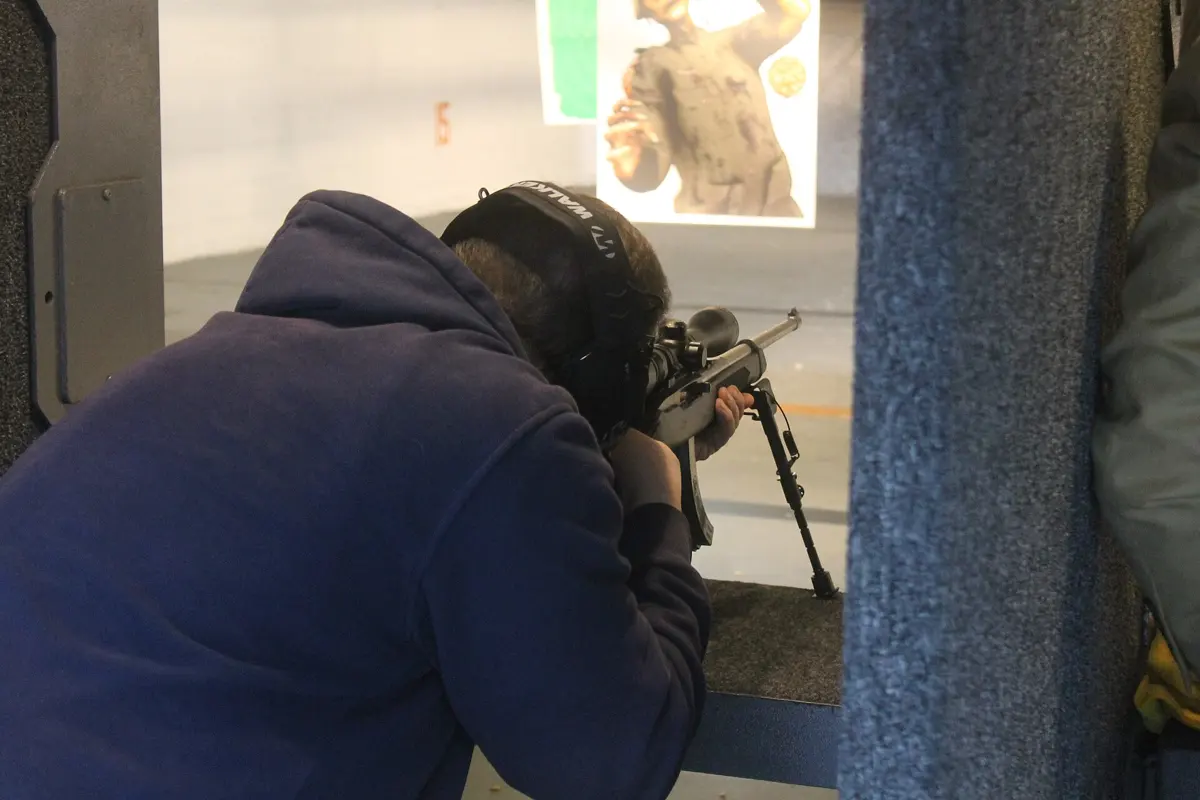 Shooter with a .22 LR rifle at an outdoor shooting range
