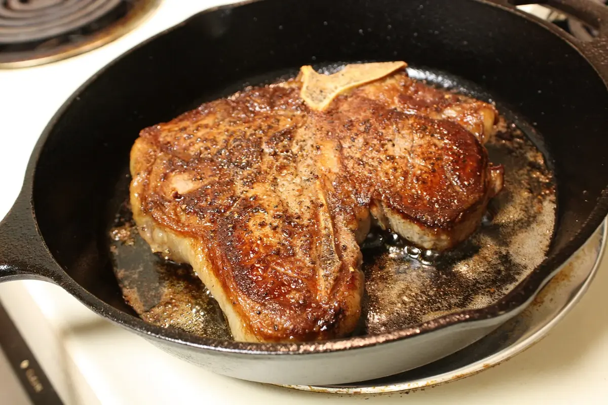 A thick porterhouse steak searing over high heat